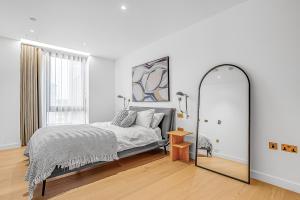 - une chambre blanche avec un lit et un miroir dans l'établissement Modern King's Cross Apartments, à Londres
