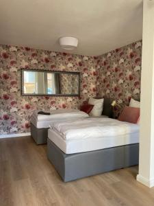 2 Betten in einem Schlafzimmer mit Blumentapete in der Unterkunft Das Haus zur Rothen Thür 2 in Arnstadt