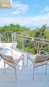 dos sillas sentadas en un patio con el océano en el fondo en Coral Garden 7 Pools, en Yomitan