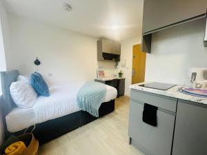a small room with a bed and a kitchen at Quaint & Cosy Studio in Stretford in Manchester