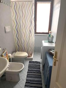 bagno con lavandino, servizi igienici e finestra di Residence Olimpo a Santa Teresa di Gallura