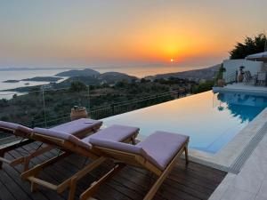 a pool with two lounge chairs and a sunset at Villa Buddha in Syvota