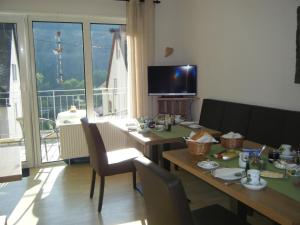 a dining room with a table with chairs and a television at Ferienweingut Hensler in Briedel