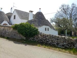 a stone wall in front of a white house at Trulli Volpe in Alberobello