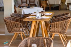 a wooden table with rattan chairs and a table with a tableablish at Plataria Seaside Resort in Plataria