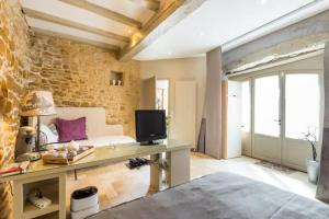 Habitación con cama, TV y pared de ladrillo. en Les Terrasses Dorées - Chambres d'hôtes de charme & Jacuzzi, en Châtillon