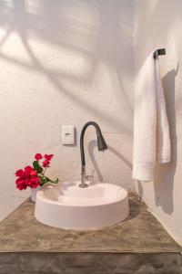 a white sink with red flowers on a counter at Pousada Morro do Caburé in Cajueiro