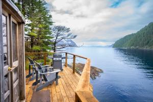 a house with two benches on a dock overlooking a lake at Orca Island Cabins in Seward