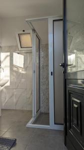 La salle de bains est pourvue d'une douche et d'une porte en verre. dans l'établissement Banana Tree House, à Ponta do Sol