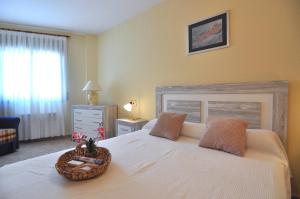 a bedroom with a white bed with a basket on it at RNET-Nautilus Roses Costa Brava in Roses +28 photos