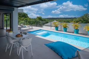 un patio con piscina, mesa y sillas en Tropic & Chic, en Sainte-Anne