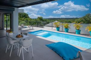 a patio with a swimming pool and a table and chairs at Tropic & Chic in Sainte-Anne