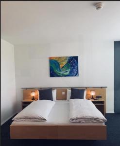 a bed with two pillows and a painting on the wall at Work Life Residence by Frauenfeld in Frauenfeld