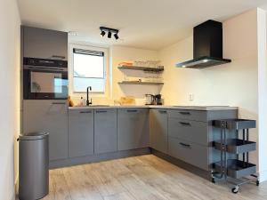 a kitchen with grey cabinets and a sink and a window at Bungalow 57 op Recreatiepark De Wielen in Sint Maarten