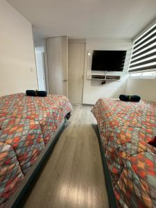 a bedroom with two beds and a flat screen tv at Rústico 804 Lago Sochagota in Paipa +23 photos