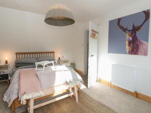a bedroom with a bed and a painting of a deer on the wall at The Cottage In The Woods in Taynuilt