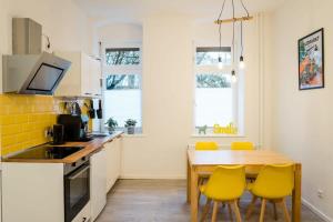 a kitchen with a wooden table and yellow chairs at Nahe Boxhagener Platz für 4 Personen in Berlin