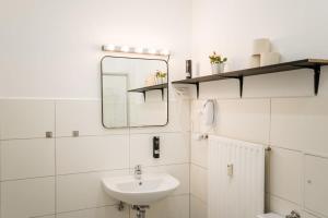 un bagno bianco con lavandino e specchio di Spacious 3BR plus AC Self Check-in Street Parking a Berlino Altre 9 foto