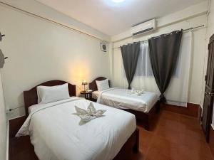 een hotelkamer met twee bedden met bloemen erop bij Champa Inn Hotel in Vang Vieng