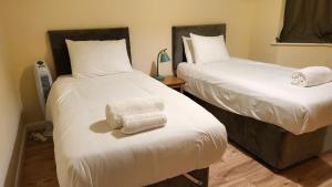 two beds in a room with two towels on the bed at Garland Modern Spacious Apartment With Garden in Edgware