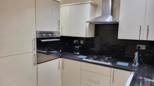 a kitchen with white cabinets and a stove top oven at Garland Modern Spacious Apartment With Garden in Edgware +18 photos