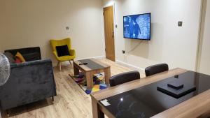 uma sala de estar com uma mesa e uma televisão na parede em Garland Modern Spacious Apartment With Garden em Edgware