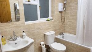 a bathroom with a toilet and a sink and a tub at Garland Modern Spacious Apartment With Garden in Edgware