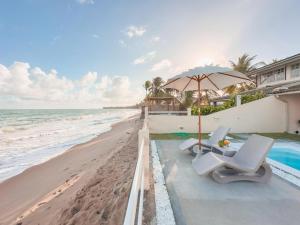 a pool with two chairs and an umbrella on the beach at Casas Wave in Maceió