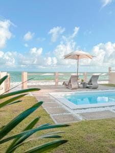 a swimming pool with an umbrella and the beach at Casa Sol Ipioca in Maceió