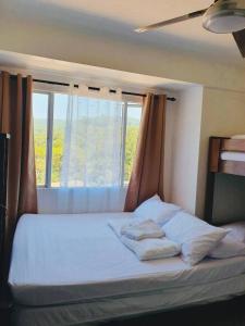 uma cama com almofadas num quarto com uma janela em BAGUIO ALBERGO HOTEL CONDO TRANSIENT by DEI GRATIA em Baguio