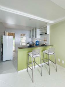 a kitchen with a green counter and two stools at Casa Sol Ipioca in Maceió