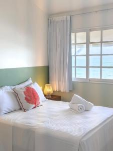 a bed with white sheets and pillows and a window at Casa Sol Ipioca in Maceió