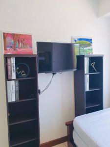 um quarto com uma cama e uma televisão e prateleiras de livros em BAGUIO ALBERGO HOTEL CONDO TRANSIENT by DEI GRATIA em Baguio