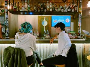 Dos mujeres sentadas en un bar hablando entre ellas en Ostello Bello Genova en Génova