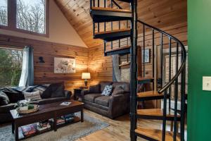 a living room with a spiral staircase in a cabin at Cozy Cabin Retreat: Tiny Trotter in Bryson City
