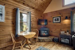 a room with a table and a fireplace in a log cabin at Cozy Cabin Retreat: Tiny Trotter in Bryson City