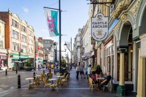 una calle con mesas y sillas y personas sentadas en mesas en Newport's heart: Steps from shops & local charm! en Newport