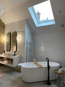 a bathroom with a tub and two sinks and a skylight at La Suite Arbane - chambre d'hôtes avec sauna chez le vigneron in Ay