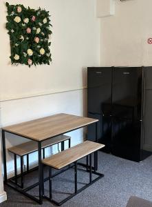 a table and bench next to a black refrigerator at Clifton Street in Middlesbrough