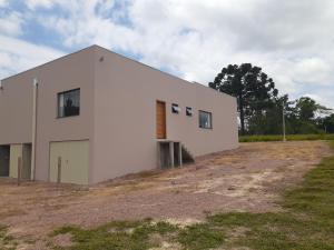 a white building on top of a field at Suítes Flor do Maracujá 01 in Ponta Grossa