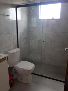 La salle de bains est pourvue de toilettes et d'une douche en verre. dans l'établissement Suítes Flor do Maracujá 01, à Ponta Grossa