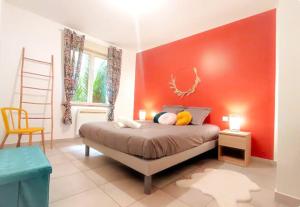 a bedroom with a bed with a red wall at Chez Augustin T2 cosy in Montauban