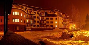 un grand bâtiment la nuit avec de la neige devant lui dans l'établissement Apartments Rokytka 112 a 208, à Rokytnice nad Jizerou