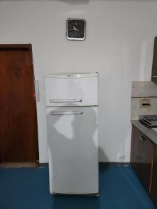 a white refrigerator in a kitchen with a clock on the wall at LUNA in Comodoro Rivadavia