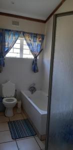 a bathroom with a tub and a toilet and a window at Panorama Chalets & Rest Camp in Graskop