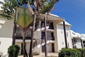 een gebouw met palmbomen ervoor bij Le Goyave – Bel appartement cosy en résidence in Le Gosier