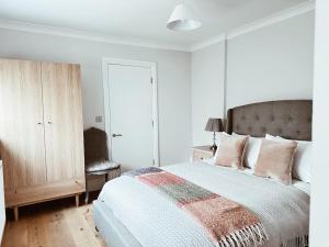 a white bedroom with a large bed with pink pillows at The Pontcanna Sapphire 2-Bed Haven in Cardiff