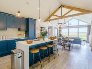 東伊爾斯利的住宿－1 Pheasant，一间设有蓝色橱柜的厨房和一个带凳子的厨房岛