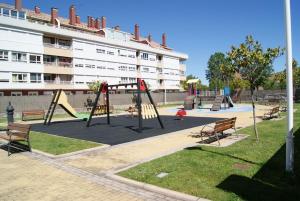 un parque infantil con columpios y bancos frente a un edificio en Apartamento con gran terraza y vistas a la catedral., en Burgos