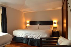 a hotel room with a large bed with white sheets at Hotel Baeza Monumental by eme hoteles in Baeza
